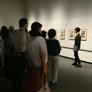 作品を解説している人と聞いている人たちの画像